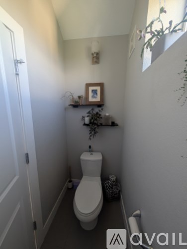 A white toilet in a small bathroom with a shelf above it.