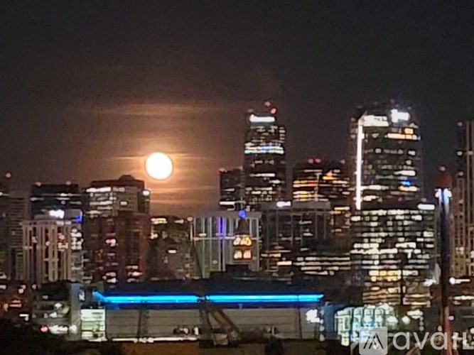 A cityscape at night with a full moon in the sky.