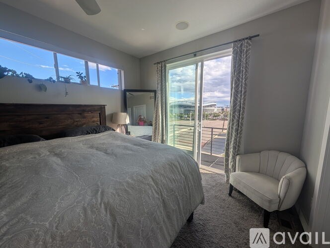 A bedroom with a large bed, a chair, and a view of the city.
