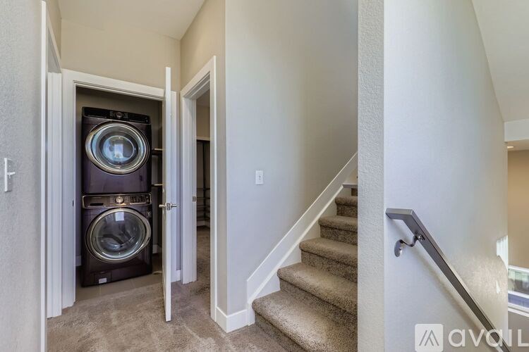 A washing machine is in a doorway between a hallway and a laundry room.