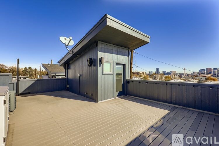 A small house with a grey roof and a green door is situated on a wooden deck.