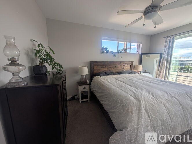 A bedroom with a bed, nightstand, and a plant.