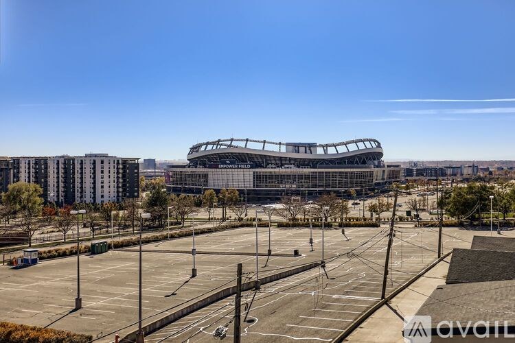 A large stadium with a curved roof is surrounded by a parking lot.