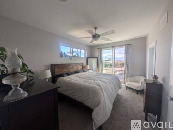 A bedroom with a large bed, a ceiling fan, and a view of the outdoors through the window.