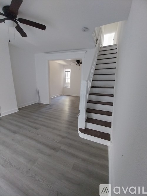 A room with a staircase and a ceiling fan.