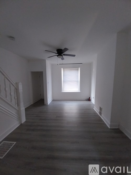 A spacious room with a ceiling fan and a window letting in natural light.