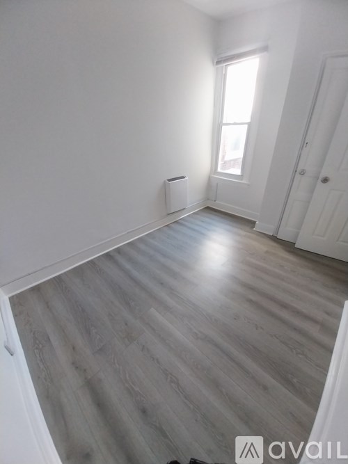 A room with wooden flooring and white walls.