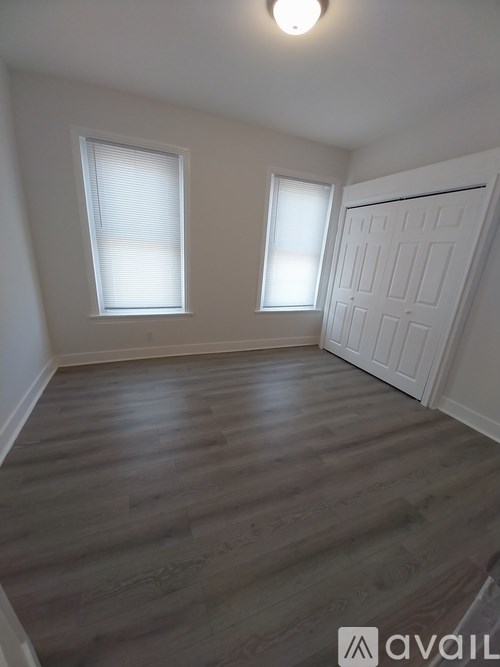 A room with wooden flooring and two windows.