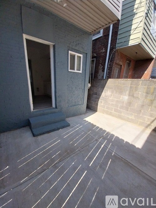 A grey building with a white window and a door.