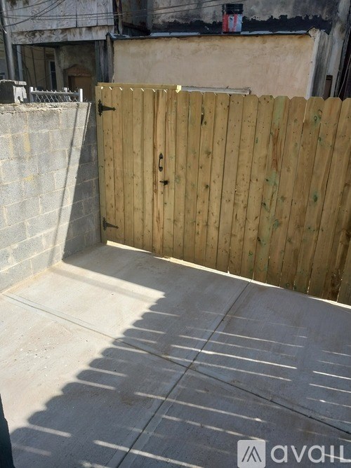 A wooden fence in front of a grey wall.