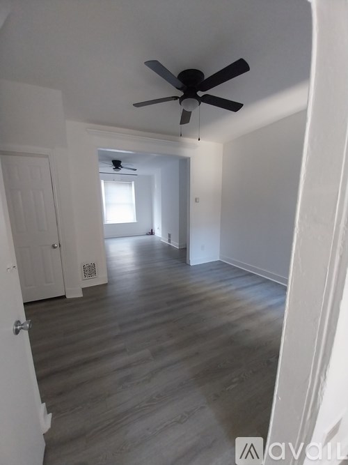 A room with a ceiling fan and wooden flooring.