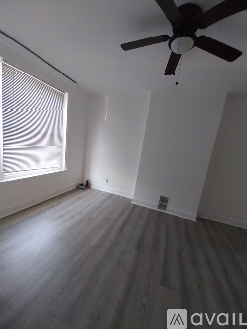 A room with a ceiling fan and a window with blinds.