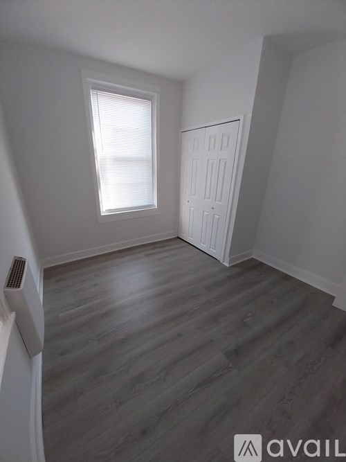 A room with a window and wooden flooring.