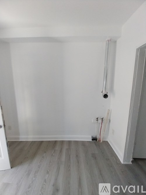 A room with white walls and a grey floor with a white door on the left and a white door on the right.