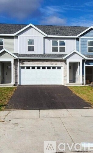 A two-story house with a garage door is for sale.