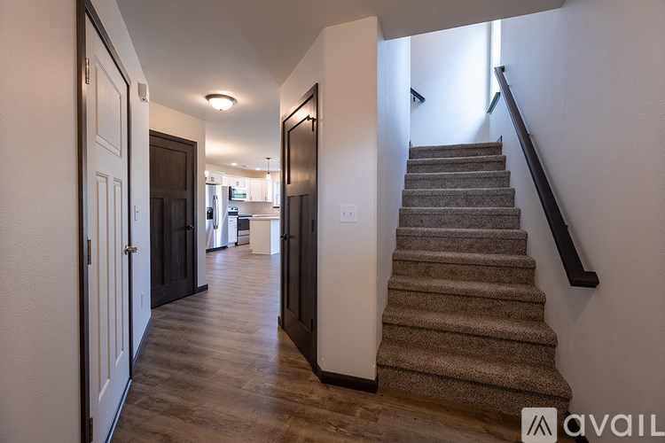 A hallway with a staircase and a black railing.