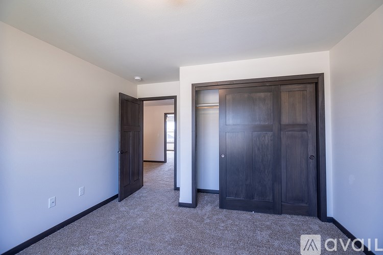 A room with a carpeted floor and two doors.