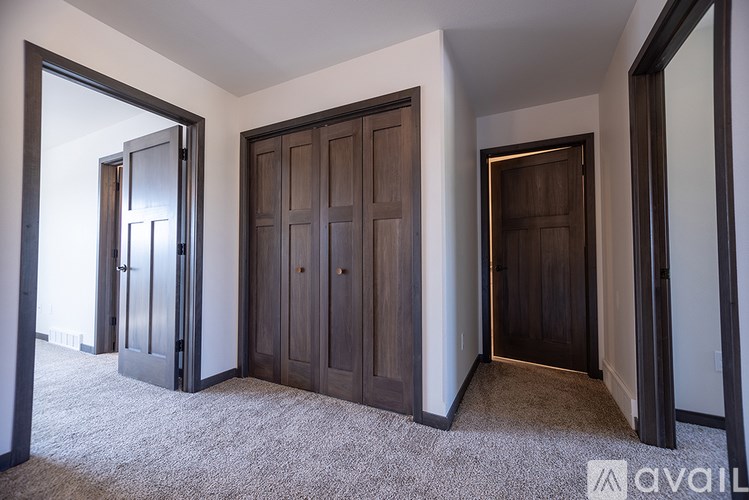 A room with a carpeted floor and three wooden doors.