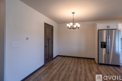 A kitchen with a stainless steel refrigerator and wooden flooring.