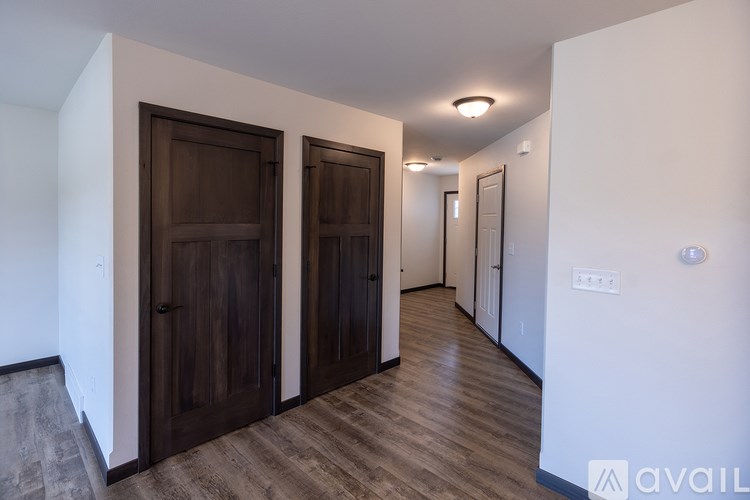 A hallway with two doors on the left and a wall on the right.