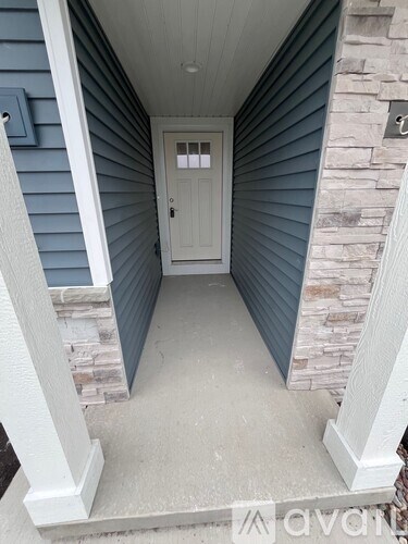 A white door is in a hallway with a stone wall on one side.