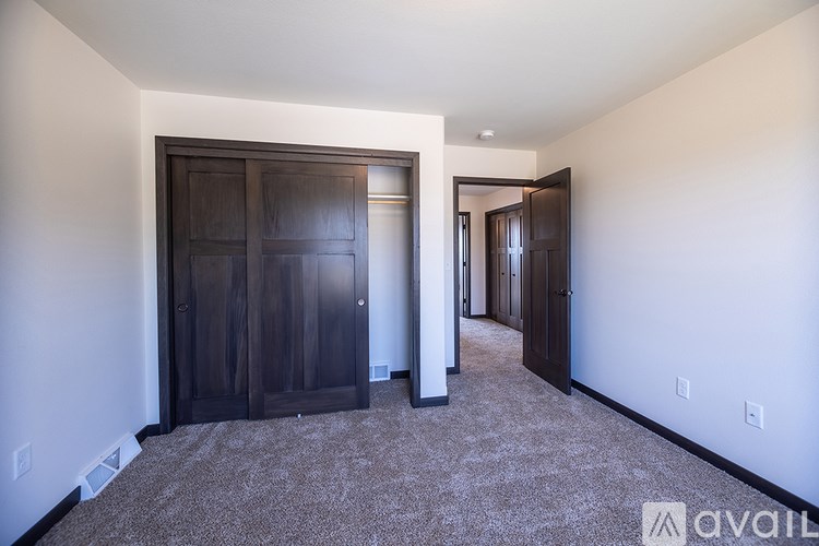 A room with a carpeted floor and two dark wood doors.