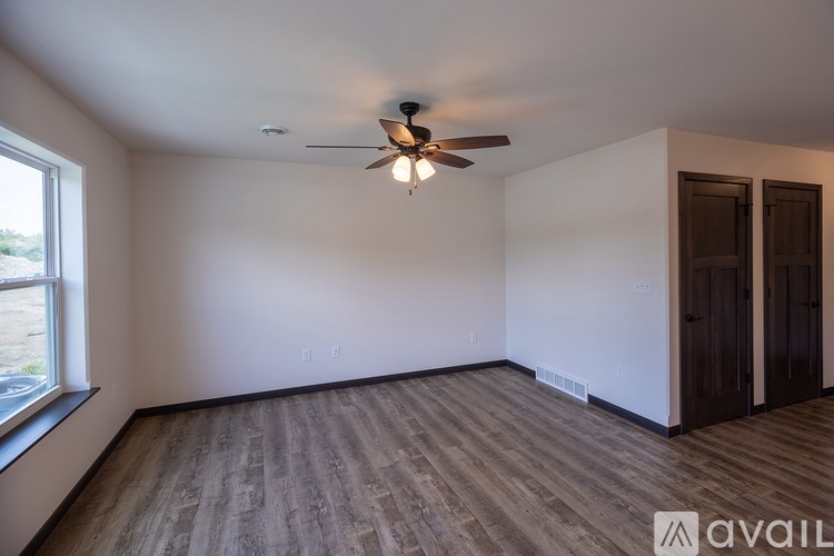 A room with a ceiling fan and wooden flooring.