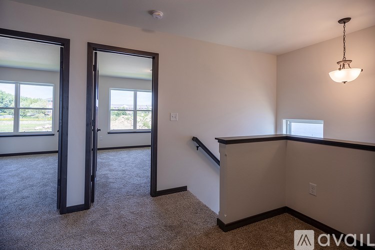 A room with a carpeted floor, a window, a door, and a hanging light fixture.