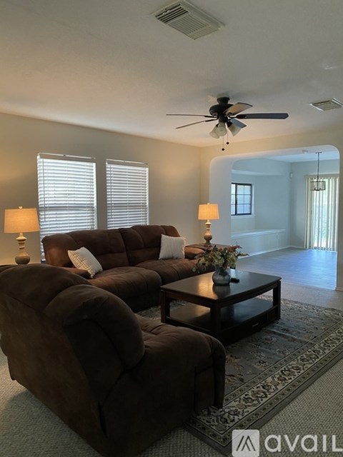 A living room with a brown couch and a ceiling fan.