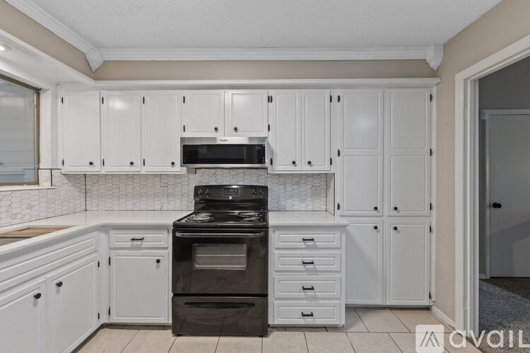 A kitchen with white cabinets and a black stove top oven.