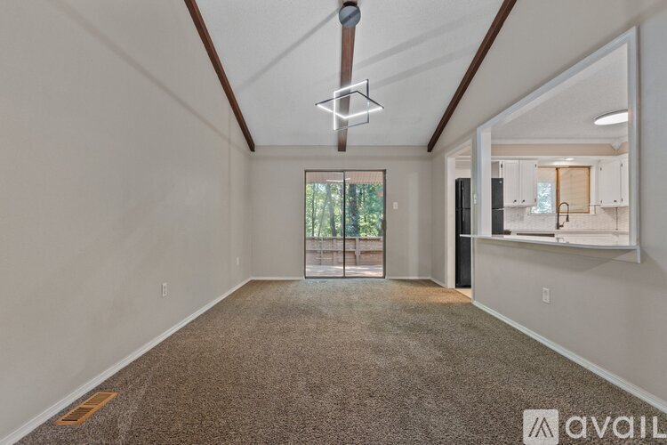 A spacious room with a carpeted floor and a ceiling fan.