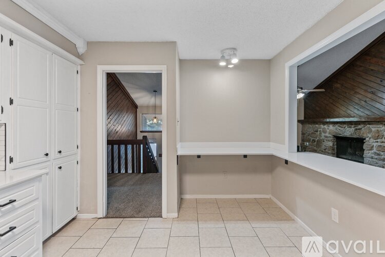 A room with a fireplace and a view of a dining area through an open door.