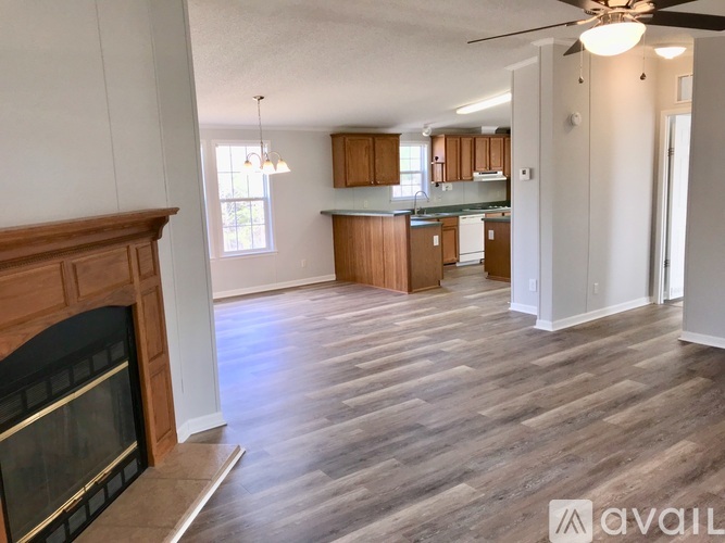 A living room with a fireplace and a kitchen in the background.