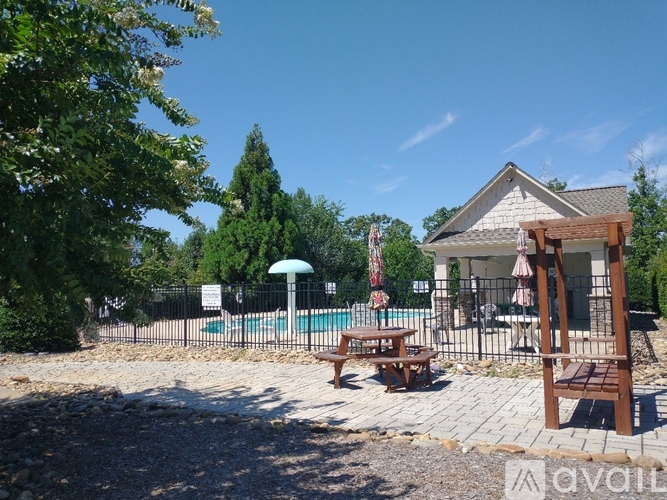 A pool area with a table and chairs and a house in the background.