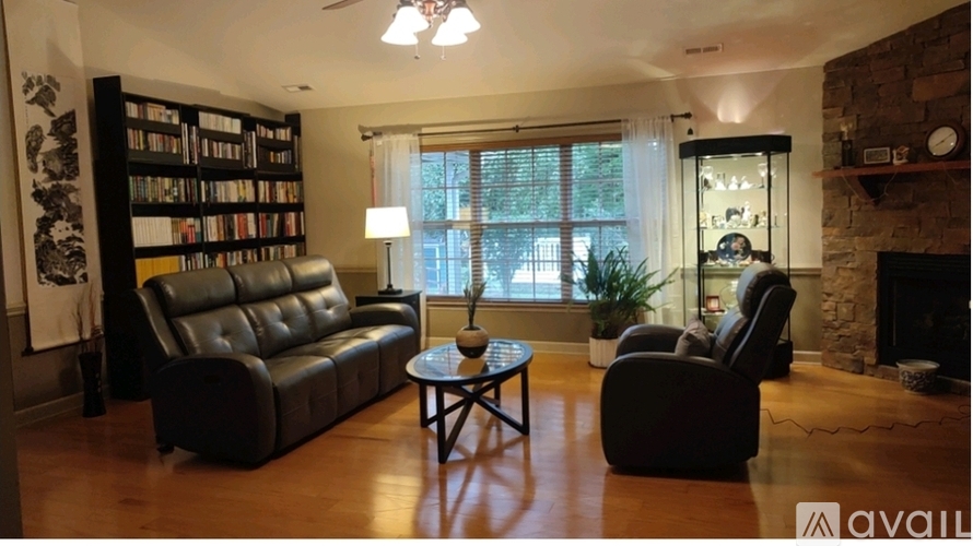 A living room with a black leather couch, a coffee table, and a fireplace.