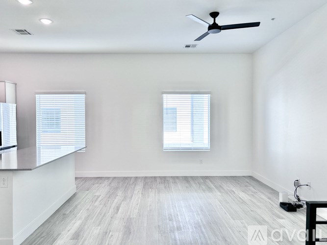A spacious room with a ceiling fan and a window with blinds.