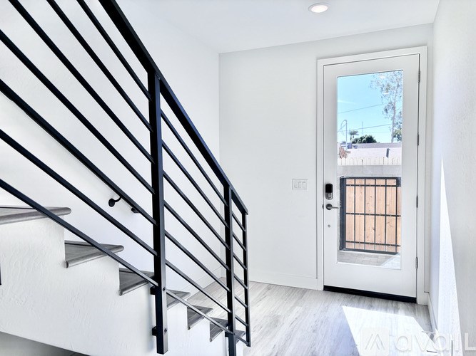 A white door with a glass window is on the right side of a staircase.