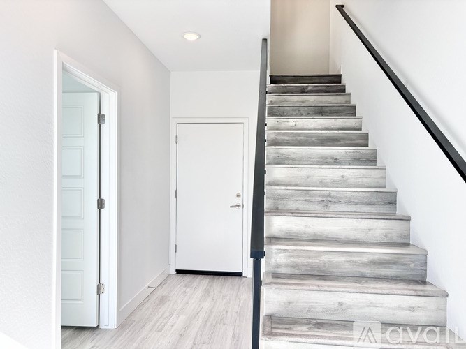 A set of stairs with a black handrail and wooden steps.