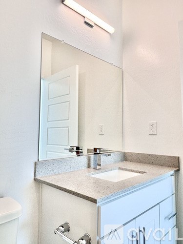 A bathroom with a sink, toilet, and mirror.