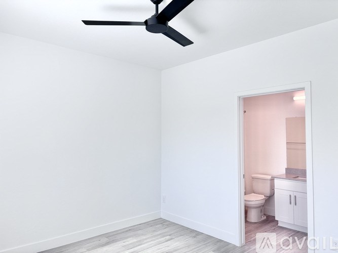 A room with a ceiling fan and a bathroom visible through the door.