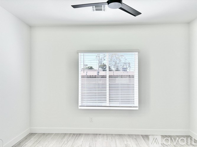 A room with a ceiling fan and a window with blinds.