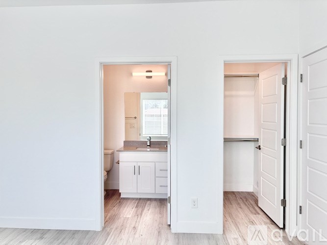 A kitchen with white cabinets and a sink is visible through an open door.