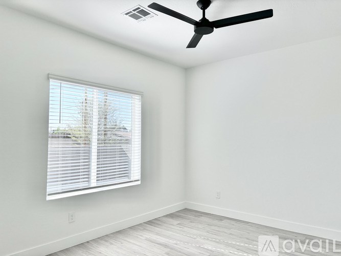 A room with a ceiling fan and a window with blinds.