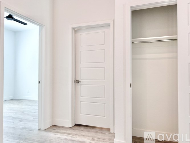 A white door is in a room with a white wall and wooden floor.