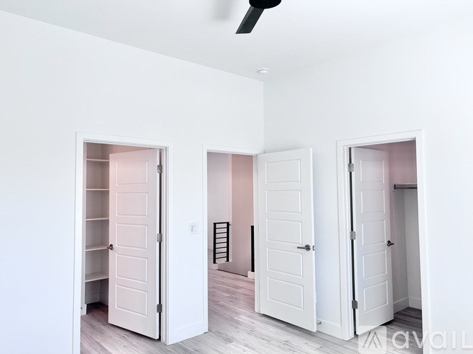 Three white doors in a room with a fan on the ceiling.