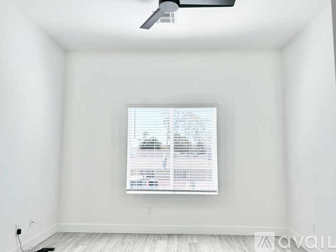 A room with a window covered in blinds and a fan on the ceiling.