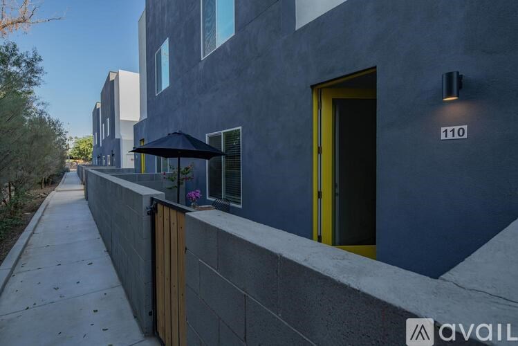 A modern building with a yellow door and a sign that reads "110" on the wall.