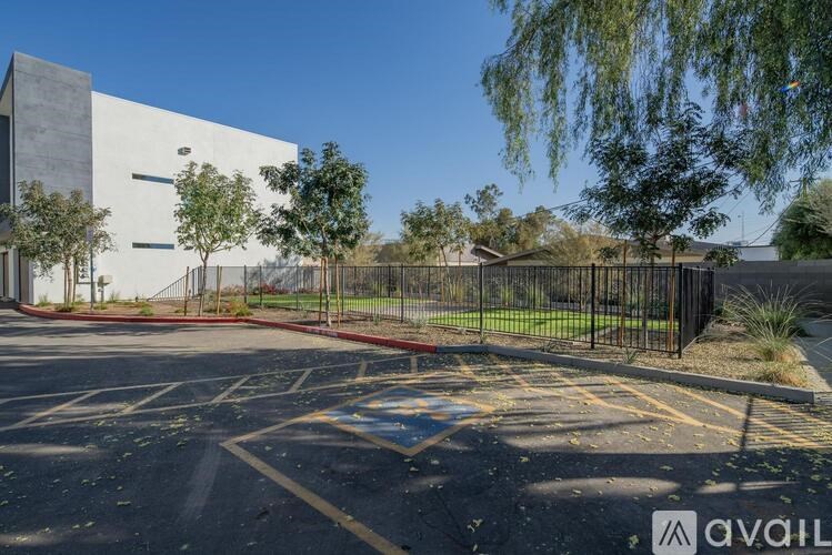 A parking lot with a building in the background and a fence surrounding it.