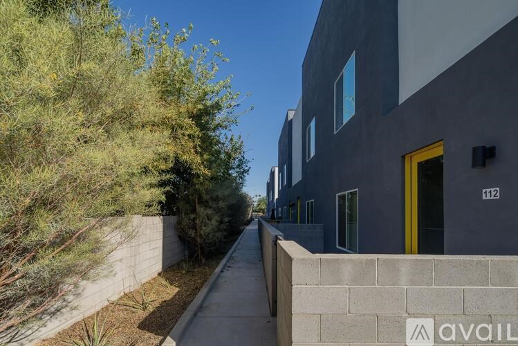 A modern building with a yellow door is numbered 112.