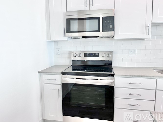 A white kitchen with a stove top oven and microwave above it.